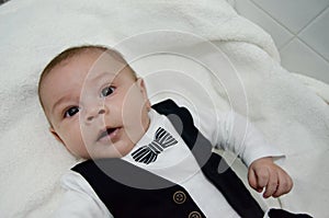 Tree months old newborn baby boy dressed like businessman with bow tie, face expresion