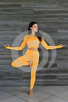 tree pose or vrksasana yoga with ukrainian woman making it indoors