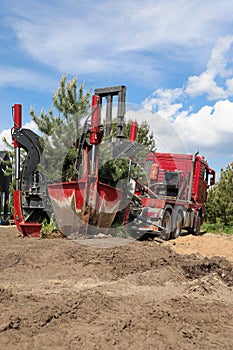 Tree transplanter heavy machine. machine for transplanting large trees. Planting large spruce trees in the park. Landscaping,