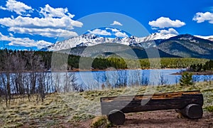 A tree trunk bench against the backdrop of the snow-capped Pikes Peak mountains, Colorado, US