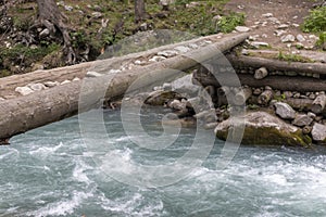 Tree trunk bridge over a river in Kumrat, Pakistan