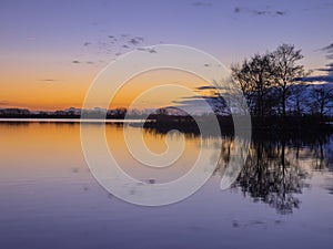 Trees and Clouds reflecting in a lake during a beautiful Sunset