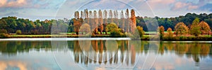 Trees and clouds reflections on a pond in autumn, panoramic landscape in Burgundy France