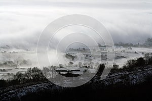 Trees and fields covered in fog on an atmospheric, moody winters day. Malvern Hills, UK