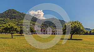 Trees frame a view of the Roman amphitheater in front of the city of Gubbio, Italy