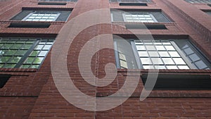 Trees reflect in the old rustic windows of renovated lofts of a classic old red brick warehouse