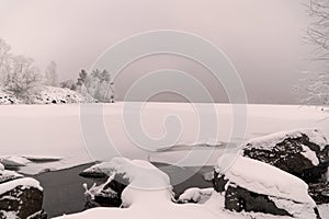 Trees and rocks in snow river in ice