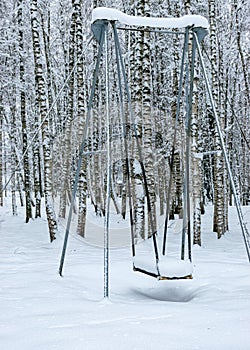 trees and tree branches covered with thick snow, snow covered swings in the park
