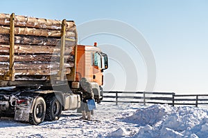 Trees truck transportation parked on snow, with driver add fuel in winter