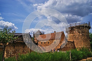 Treigny, France - July 13 2019 : Tourists visiting the Guedelon castle and its castle walls, with the GreatHall in the background