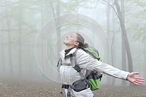 Trekker breathing stretching arms a foggy day in a forest