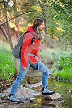 Trekker crossing a creek in a forest.