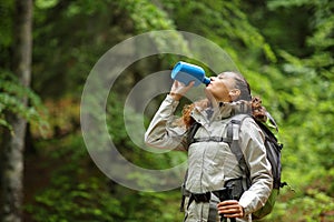 Trekker drinking water from canteen in a forest