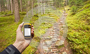 A trekker is finding the right position in the forest via gps in a cloudy autumnal day