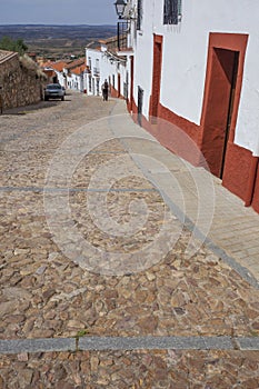 Trekker going down a  steep street of Hornachos, Spain