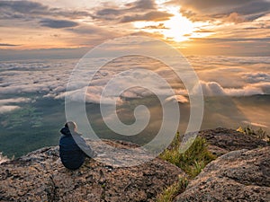 Trekker sitting on the mountain with Beautiful Sunrise and sea of mist in the morning on Khao Luang mountain