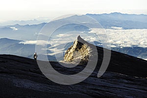 Trekker standing on Kinabalu mountain with south peak  and mountain range in background