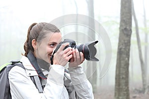 Trekker taking photos with dslr camera in a forest