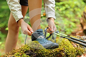 Trekker tying shoelaces of boots in a forest