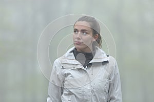 Trekker walking in a foggy forest looking at side