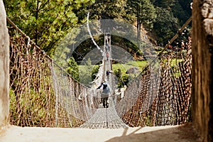 Trekkers and Sherpa crossing a suspension iron bridge in Everest base camp.