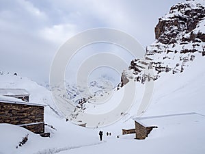 Trekkers walking on the snow mountain pass with the lodges along the way