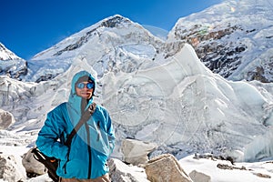 Trekkes is posing at camera in front of huge glacier falling fro