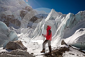 Trekkes is posing at camera in front of huge glacier falling fro