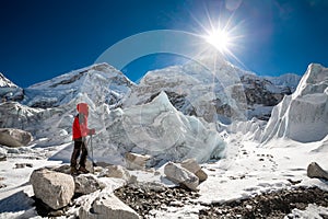 Trekkes is posing at camera in front of huge glacier falling fro