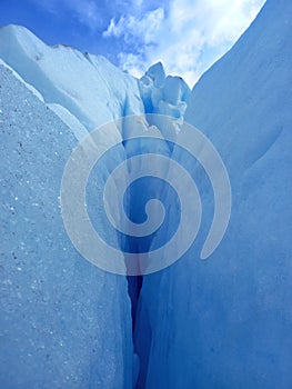 Glacier crack background under blue sky. Trekking, adventure and extreme nature