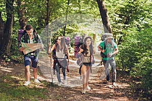 Trekking, camping and wild life concept. Four best friends are hiking in the spring woods, the guy is checking the route on a map,
