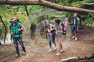 Trekking, camping and wild life concept. Four best friends are hiking in the spring woods, ladies are talking and laughing, all ar