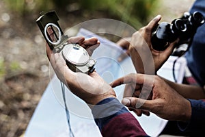 Trekking couple using map and compass in a forest