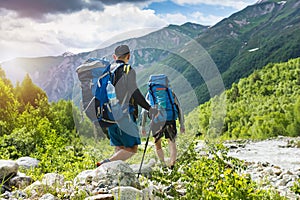 V hory. hora turistika. turisté batohy trampovat na skalnatý způsob nejblíže řeka. divoký příroda krásný zobrazení 