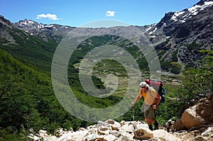 Trekking in Patagonia, Man with big backpack walking up on mountainside with view of green Rucaco valley in Nahuel Huapi photo