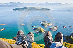 Trekking shoes on feet of couple of travelers hikers sitting on top of the mountain