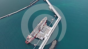 Tremendous oil tanker attached to white pier bird eye view