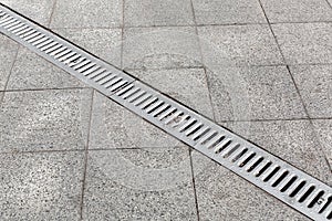 Trench drain gray with steel purification grate on granite stone tile.