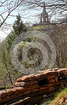 trench dug into the ground with sandbags for protection and the Ossuary of Monte Cimone visible in northern Italy