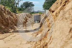 The trench for the laying and installation of water pipes with aligned and compacted base.The reinforced concrete well is covered