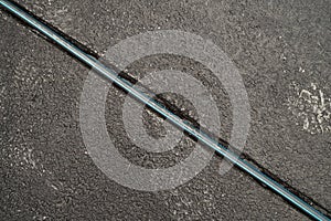 A trench on the pavement in asphalt with a cable, top view