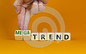 Trend or megatrend symbol. Businessman turns wooden cubes and changes words trend to megatrend. Beautiful orange table, orange