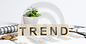 TREND word on wood blocks concept with chart, coins, notebook and glasses