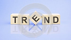 Trend - word is written on wooden cubes on a blue background. close-up of wooden elements