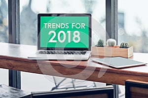 Trends for 2018 word in laptop computer screen with tablet on wood stood table in at window with blur background,Digital Business