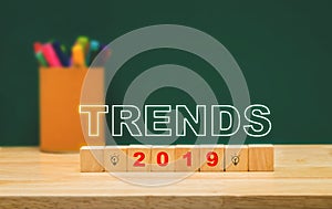 Trends 2019 on wood cube with colorful pen box on wood table with green blackboard wall.education future concept