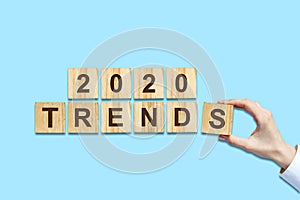 2020. Trends. Female hand makes up words from wooden blocks. Isolated on a blue background. New Year Trends Concept. B