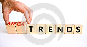 Trends or megatrends symbol. Businessman turns cubes and changes words trends to megatrends. Beautiful white table, white