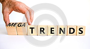 Trends or megatrends symbol. Businessman turns cubes and changes words trends to megatrends. Beautiful white table, white