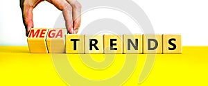 Trends or megatrends symbol. Businessman turns cubes and changes words trends to megatrends. Beautiful yellow table, white